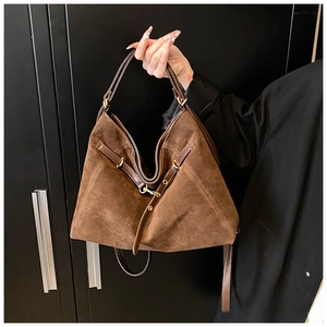 Detail of dark brown hobo shoulder bag featuring suede texture and gold buckle accents