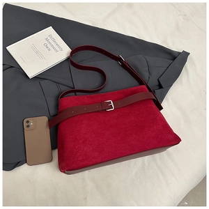 Détail du sac cabas en daim bordeaux avec boucle sur fond de costume gris