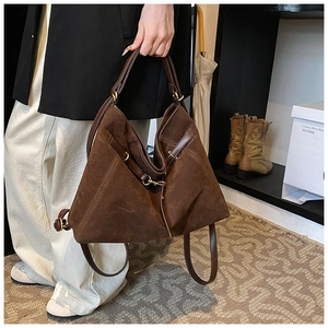 Detail of a large brown suede tote bag featuring high-quality golden metal hardware accents