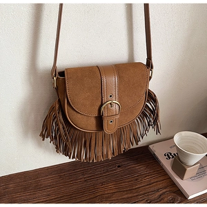 Detail shot of caramel brown saddle bag showing suede texture and retro fringe design