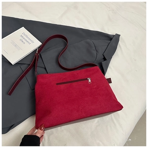 Détail du sac cabas en daim rouge montrant la poche zippée et la bandoulière en cuir
