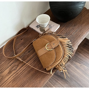Close-up of brown suede saddle bag with vintage fringe details and gold metal buckle
