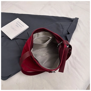 Gros plan du sac fourre-tout bordeaux montrant la doublure grise avec poche zippée