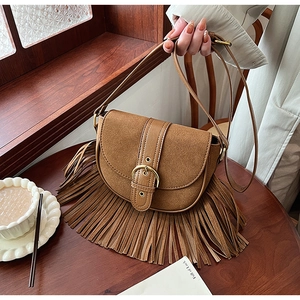 Detailed view of vintage brown crossbody bag with suede fringe and golden buckle