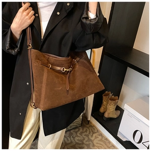 Detailed view of brown suede tote bag with slim straps and golden adjustable buckle