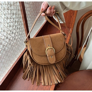 Detail of a brown suede saddle bag featuring long fringe tassels and golden metal buckle