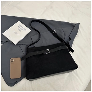 Gros plan du sac cabas en daim noir avec boucle argentée sur une veste grise