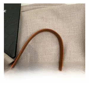 Dettaglio del manico in pelle marrone con cuciture accurate su questa borsa elegante