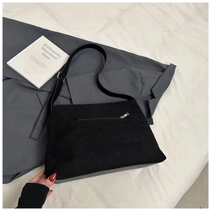 Détail de la poche zippée arrière sur un sac cabas en daim noir avec un décor minimaliste