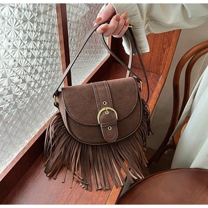 Close-up of vintage brown suede saddle bag with fringe details and metal buckle