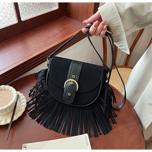 Close-up of vintage black matte saddle bag featuring gold buckle and long tassel details