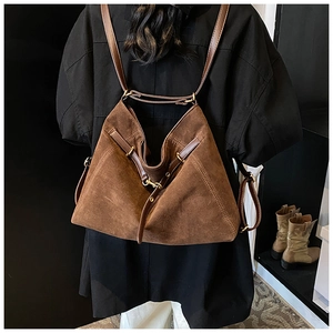 Detail of dark brown suede backpack with leather straps and gold metal hardware