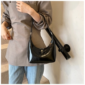 Borsa a mezzaluna nera lucida indossata da una modella con dettaglio doppia zip