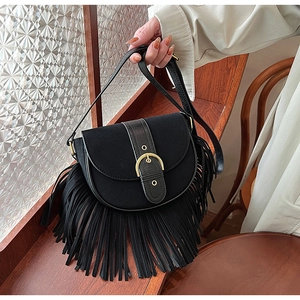 Close-up of black matte saddle bag featuring gold metal hardware and long fringe tassels