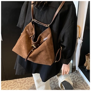 Close-up of vintage brown suede backpack with adjustable leather straps and gold metal buckles