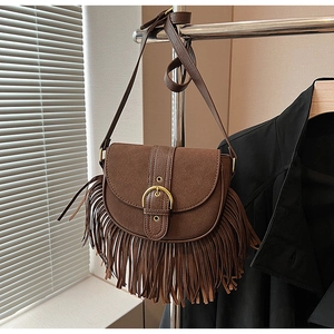 Detail of vintage brown suede saddle bag with leather fringe tassels and gold buckle