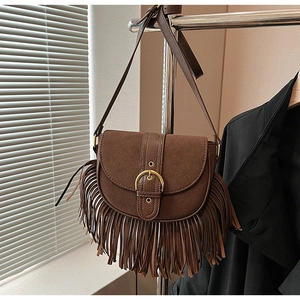 Detail of vintage brown suede crossbody bag featuring long fringe and gold hardware