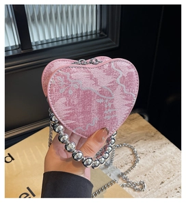 Dettaglio borsa cuore rosa con manico di perle argentate e tracolla a catena