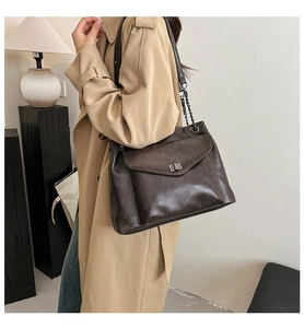 Dettaglio borsa tote vintage marrone con serratura rotante in metallo e tracolla a catena