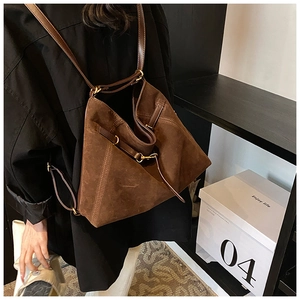 Detail view of coffee suede multipurpose bag featuring gold hardware and leather drawstrings