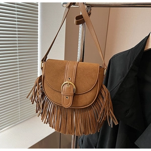 Detail shot of a brown vintage saddle bag featuring suede texture and long tassels