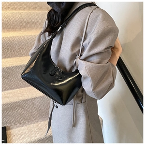 Elegante borsa a mezzaluna nera in vernice lucida abbinata a un completo grigio