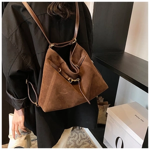 Detail of dark brown vintage suede backpack with gold hardware and leather straps
