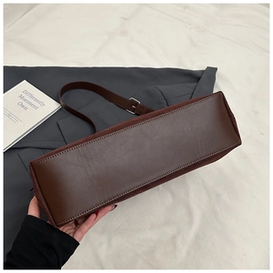 Vue détaillée du fond rectangulaire de ce sac en cuir café foncé avec coutures en daim
