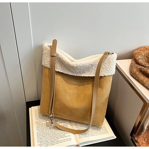Dettaglio della borsa a tracolla in pelle scamosciata e lana d'agnello su un libro
