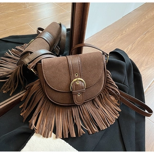 Detail of brown vintage saddle bag with long tassels and gold metal clasp in a mirror view