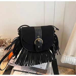 Detailed macro view of black saddle bag with vintage tassels and gold metal buckle