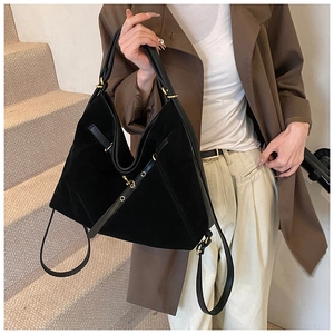 Close-up of black suede tote bag detail with premium matte texture and gold hardware