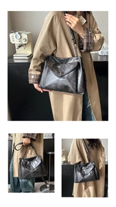 Dettaglio borsa tote retrò nera con catena, chiusura a scatto argentata e texture pelle