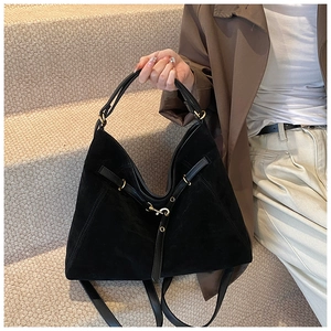 Detail of black suede tote bag with elegant leather straps and gold metal hooks