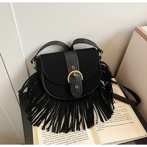 Close-up of black matte saddle bag featuring long tassels and a large gold metal buckle
