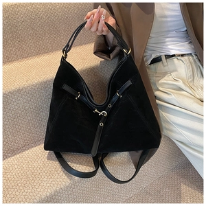 Detail of vintage black suede tote bag showing soft texture and gold buckle accents