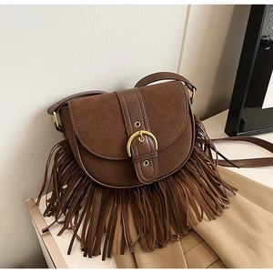 Detail of vintage brown suede saddle bag showing long fringe and retro gold buckle strap