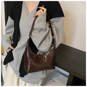 Dettaglio di una borsa hobo a mezzaluna marrone scuro con finitura lucida e doppia zip