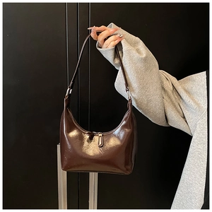 Dettaglio ravvicinato della borsa hobo in pelle verniciata marrone scuro lucida da donna