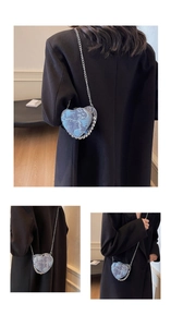Dettaglio borsa a cuore in denim blu con perline argentate e tracolla a catena sottile