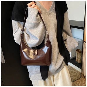 Dettaglio della borsa hobo marrone scuro in pelle lucida con doppia cerniera e fibbie