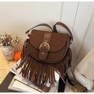 Close-up of vintage brown suede saddle bag featuring long tassels and metallic buckle