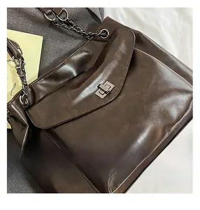 Dettaglio borsa vintage marrone scuro con chiusura a rotazione e tracolla a catena