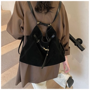 Back view of model wearing a black matte suede multi-purpose backpack with gold hardware