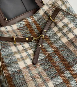 Detail der Tweed-Karo-Textur mit eleganten goldenen Metallelementen an der Tasche