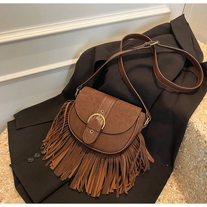 Detail of vintage brown tassel crossbody bag with golden ring buckle and suede texture
