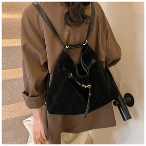 Close-up of matte black suede multi-way backpack with golden buckle on a female model
