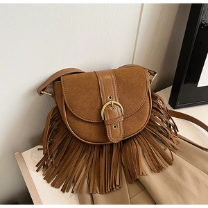 Close-up of vintage brown suede saddle bag with fringe details and metal buckle