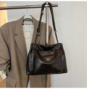 Dettaglio della borsa tote marrone scuro con chiusura a scatto e tracolla a catena
