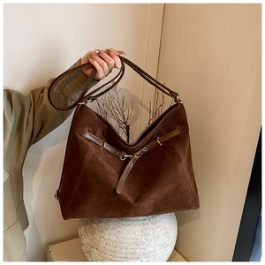Macro view of vintage dark brown suede tote bag with gold buckle and adjustable strap